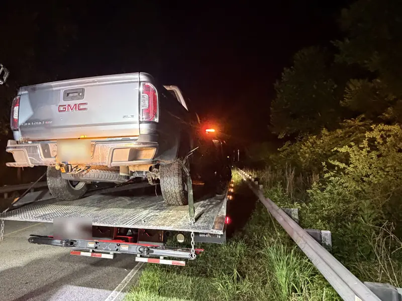 Pickup truck on the bed of a Dependable rollback at night